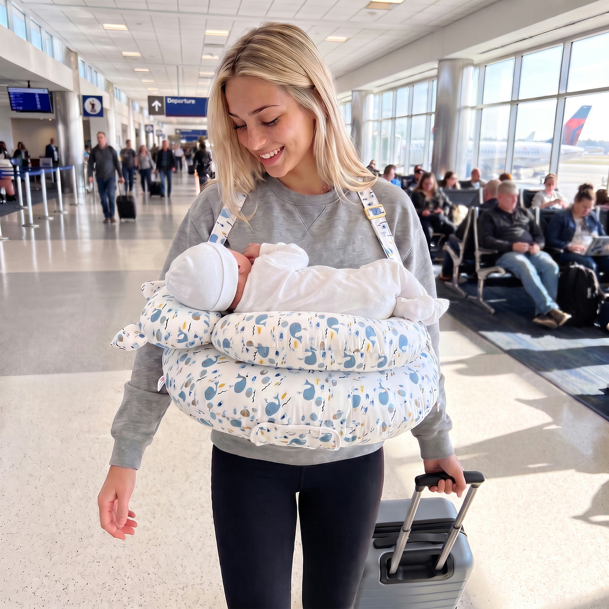 Mom walking through the airport wearing the Oinkie nursing pillow with her baby